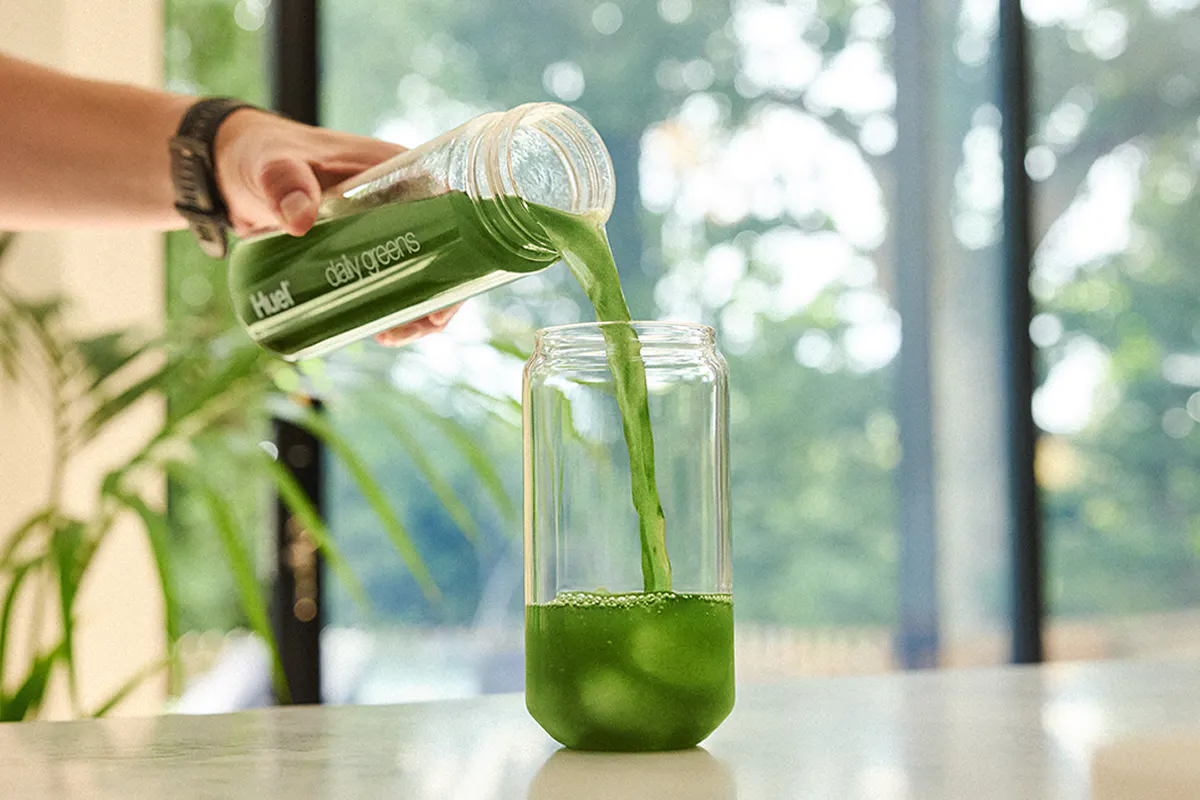 Pouring Daily Greens in morning sunlight